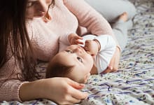 A Mother and baby child on a bed.