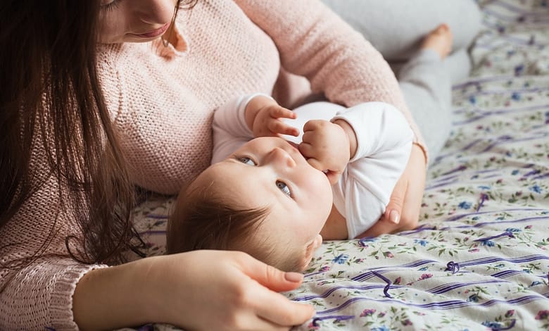 A Mother and baby child on a bed.